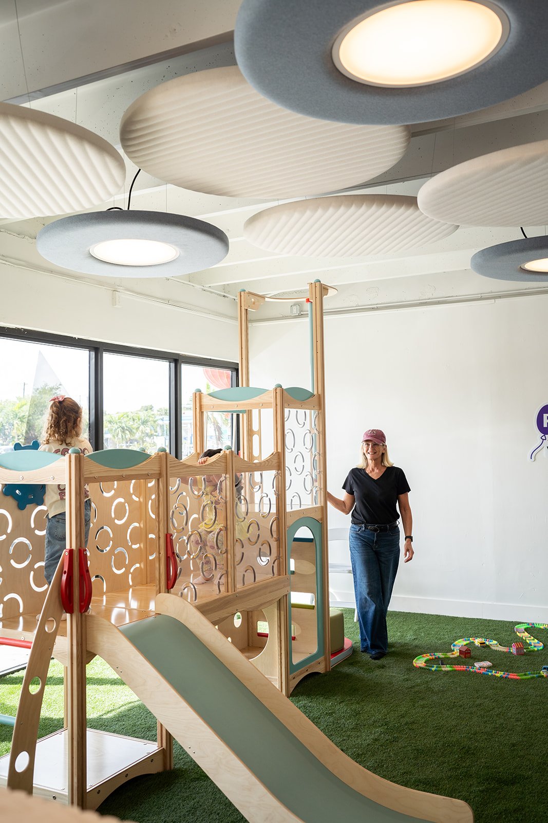 Stefanie beside the wooden play structure and slide at Rise Village, the preschool play space the team built and ran